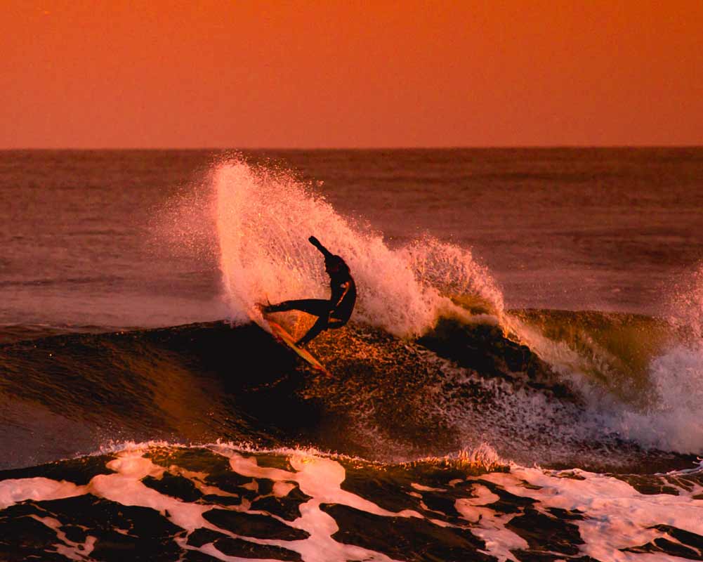 Surfer sur une vague pendant le coucher de soleil